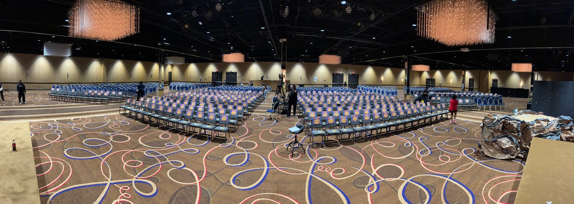 A large room filled with rows of chairs and chandeliers.
