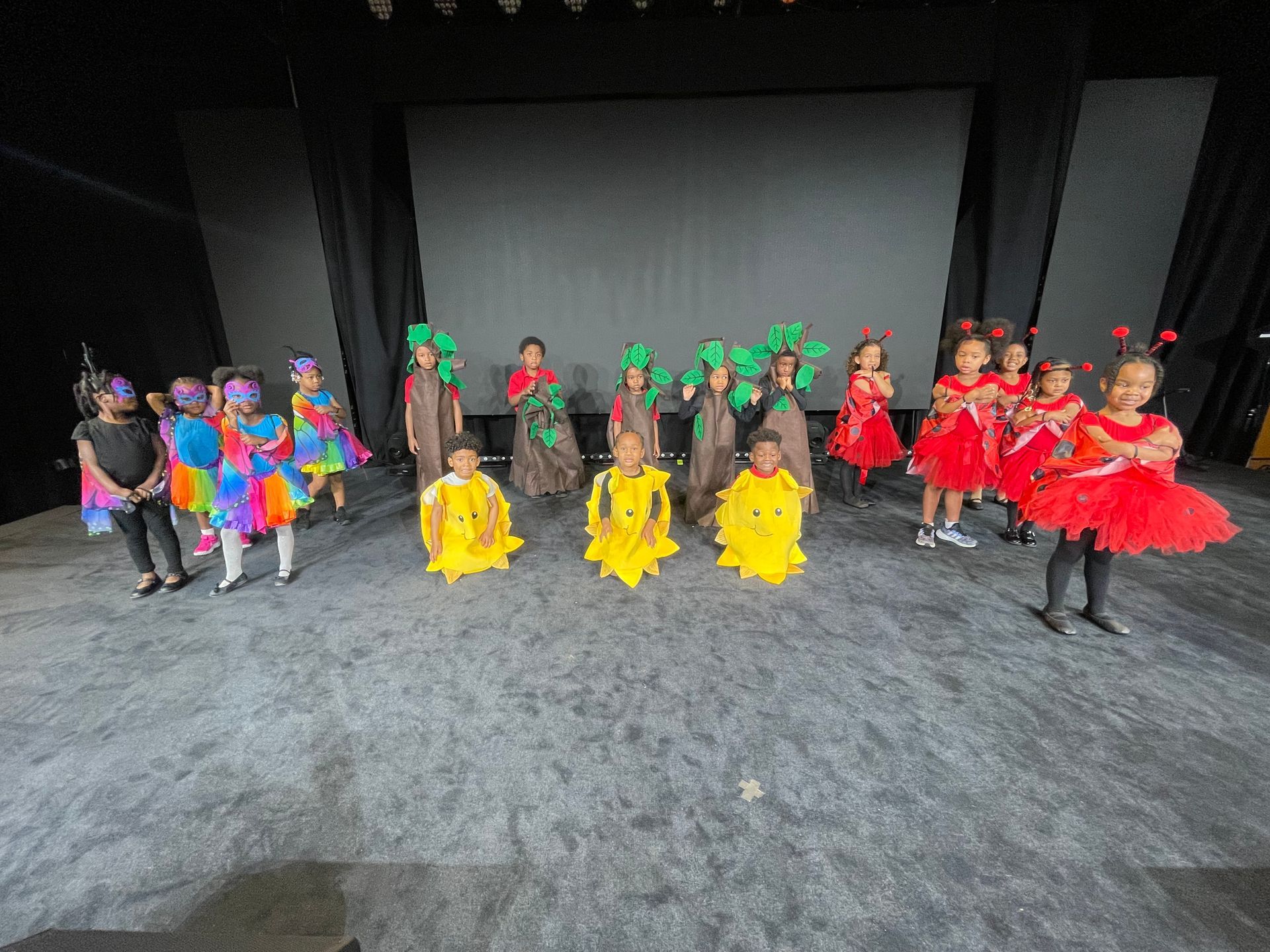 A group of children in colorful costumes are standing on a stage.