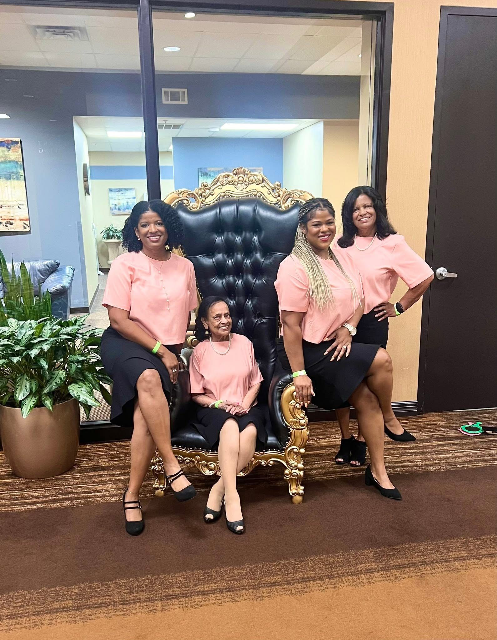 A group of women are posing for a picture while sitting on a chair.