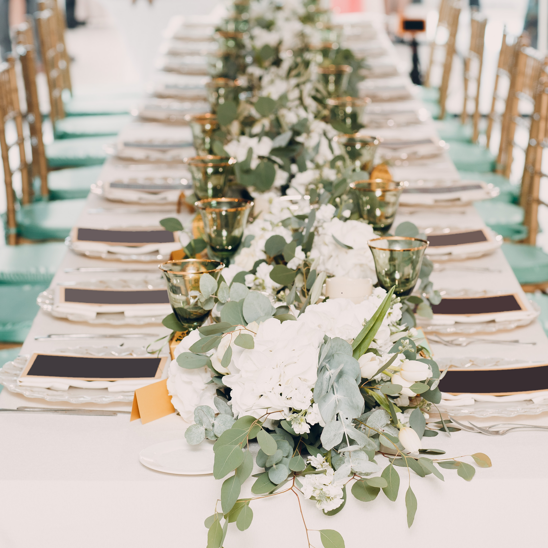 A long table with plates , glasses , and flowers on it.