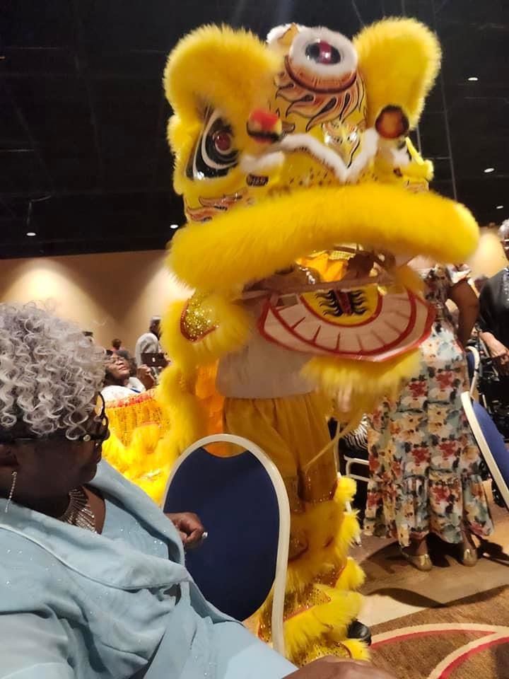 A woman is sitting in front of a lion costume
