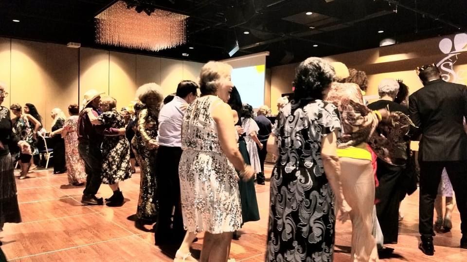 A group of people are dancing in a large room.