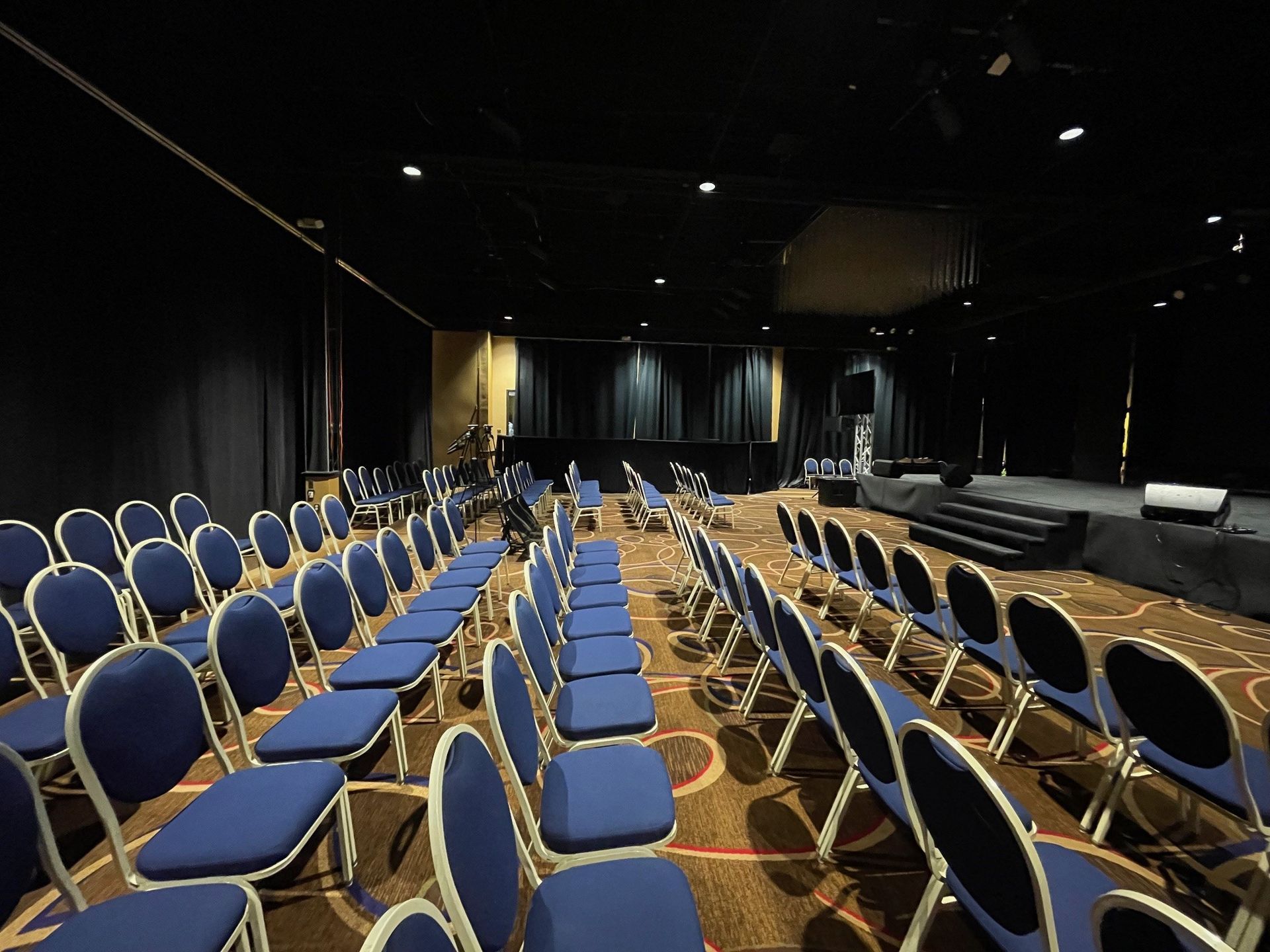A large auditorium with blue chairs and a stage