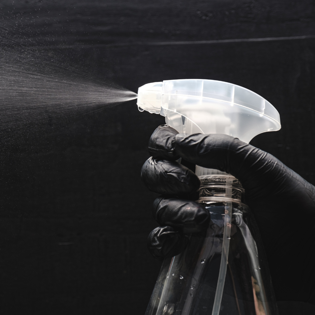 A person wearing black gloves is spraying a spray bottle.
