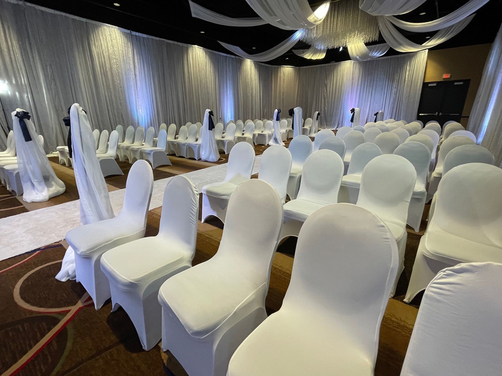Rows of white chairs are lined up in a large room.