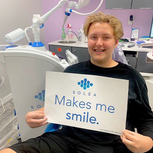 A man is holding a sign that says solea makes me smile