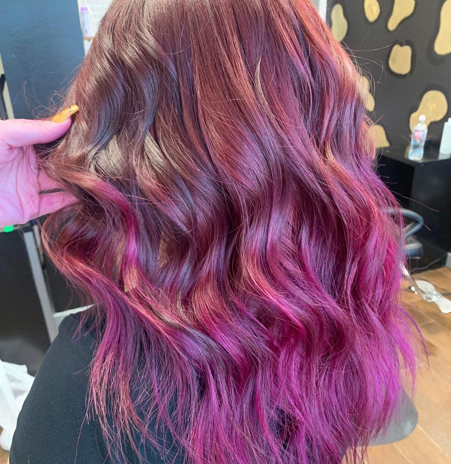 Woman's wavy hair with a dark red to bright pink ombre effect.