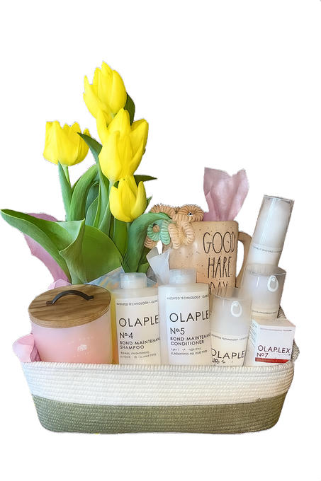 Basket with yellow tulips, skincare products, candle, and mug, likely a gift.