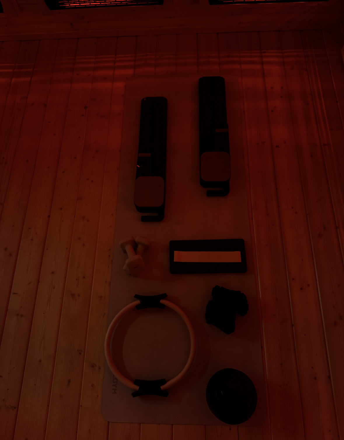 Pilates equipment, including two vertical black bars, a ring, and various small accessories, arranged on a wooden floor.