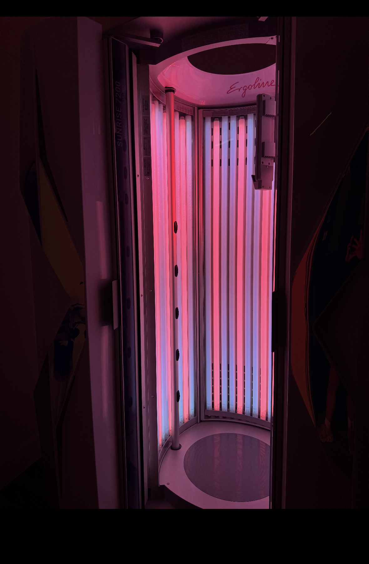 Tanning bed with pink and white lights aglow. Interior view.
