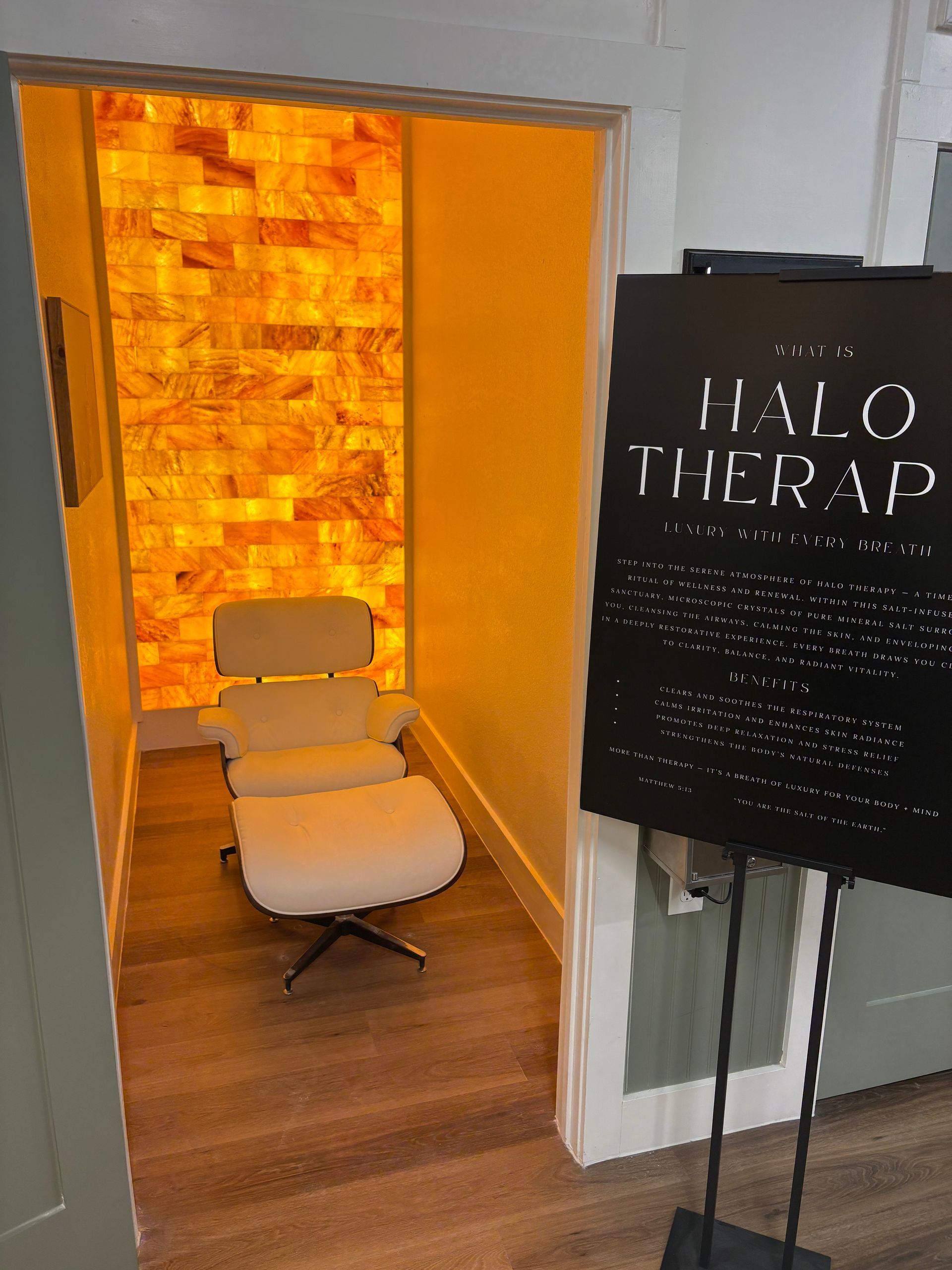 Salt therapy room with illuminated salt wall, white chair, and sign.