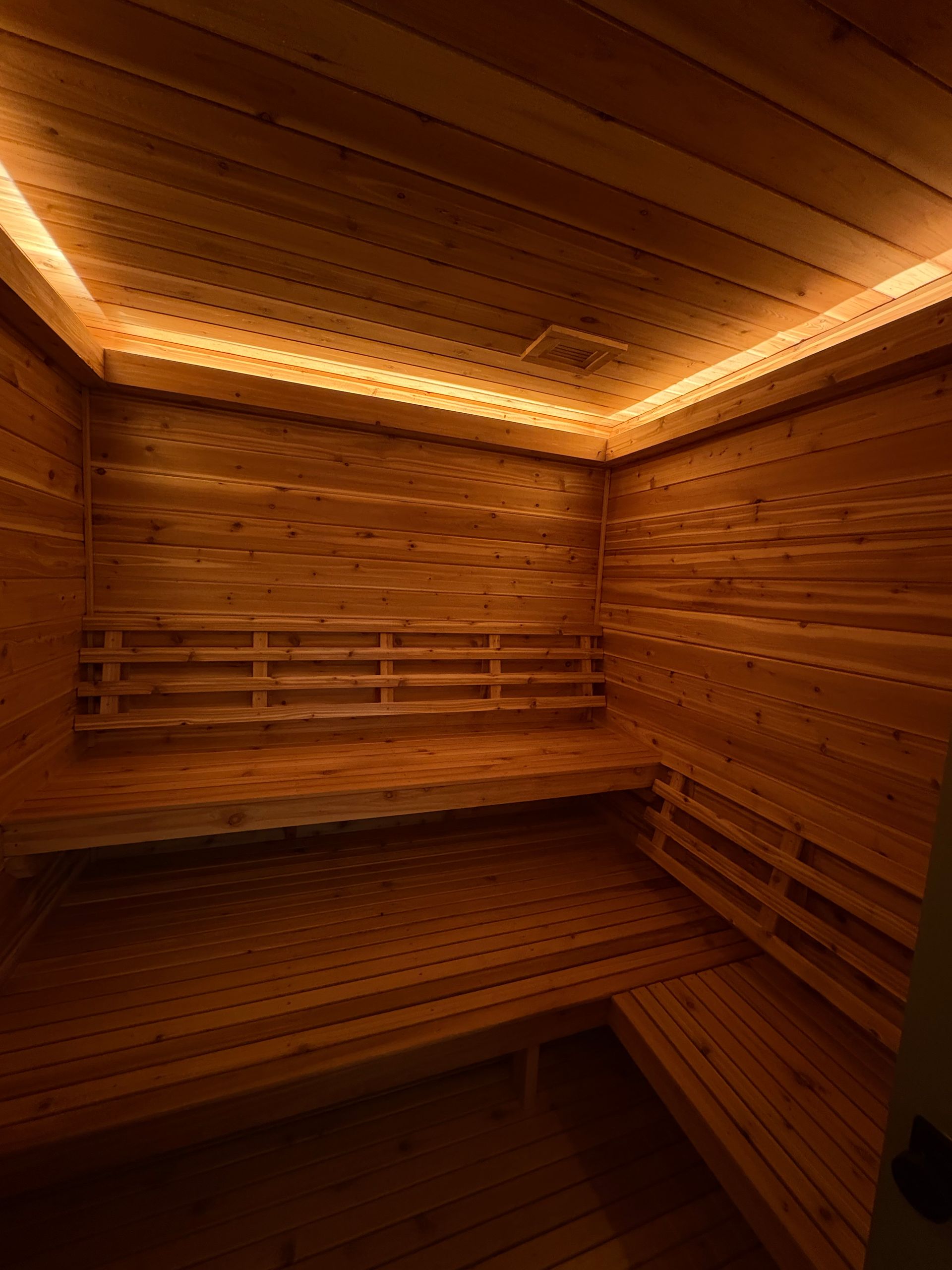 Wooden sauna interior with benches, illuminated by soft lighting.