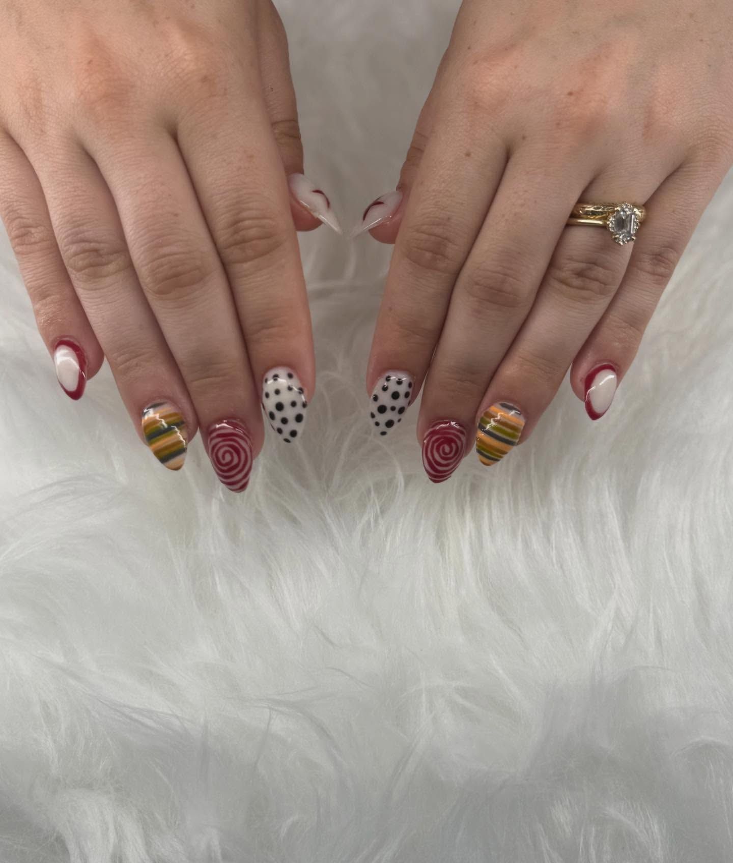 Hands with almond-shaped nails decorated with a variety of designs in red, white, black, and gold.