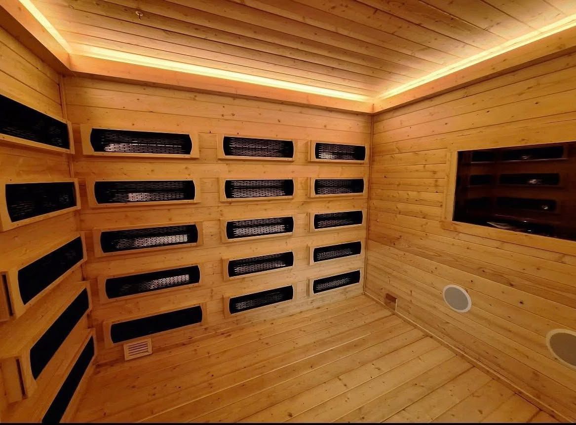 Wooden sauna interior with infrared panels on walls and recessed lighting.
