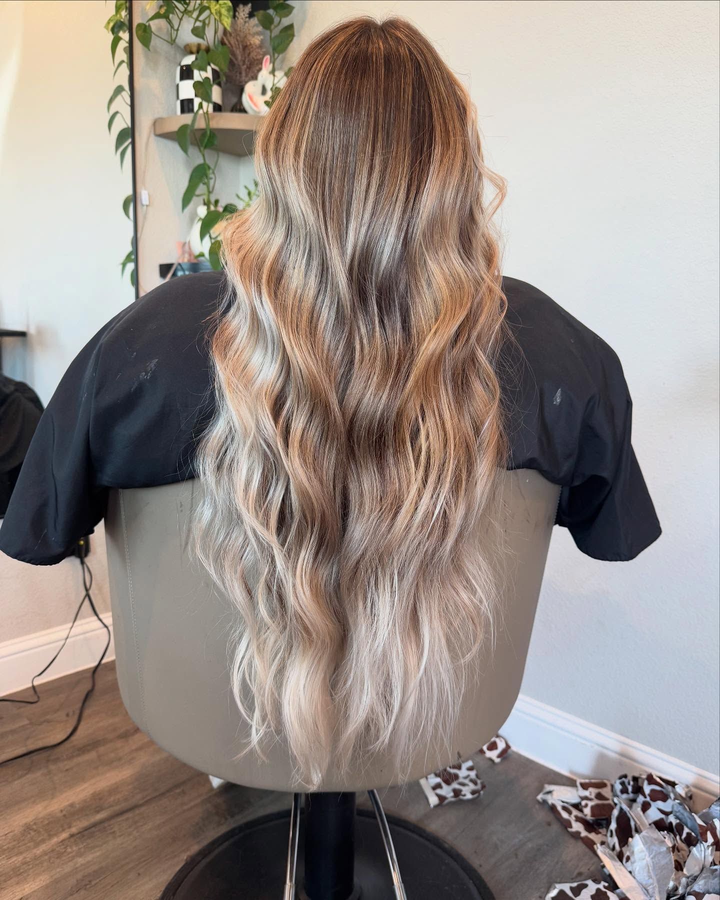 Woman in salon chair with long, wavy, blonde and brown hair.