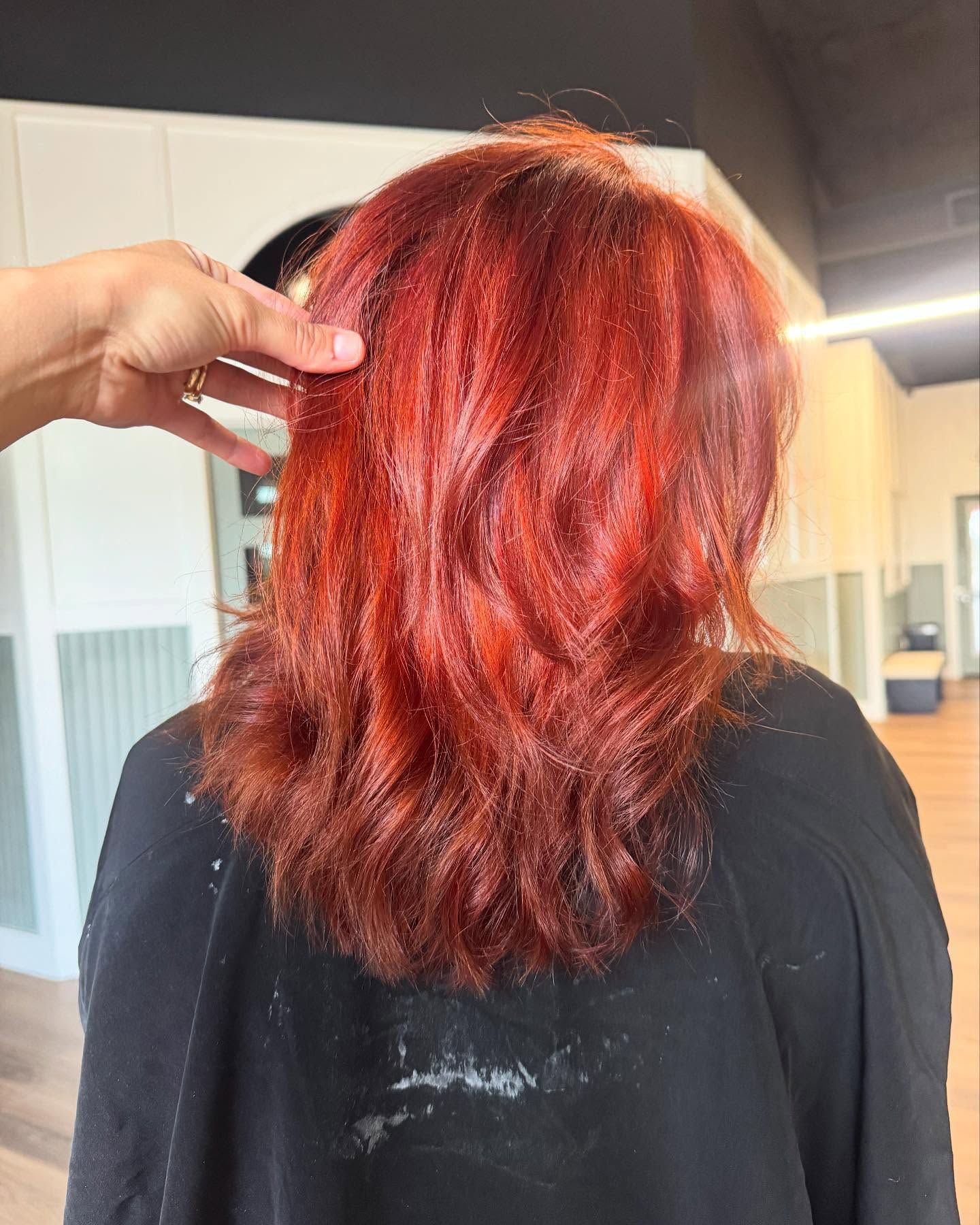 Red hair styled in salon; hand touching the hair.