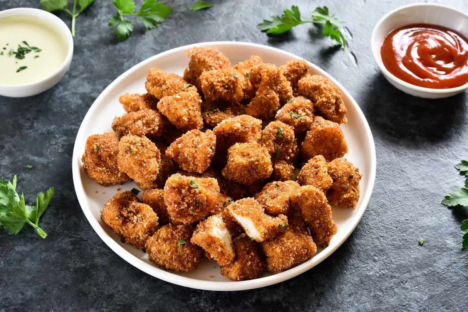Plate of crispy fried nuggets with ketchup and sauce.