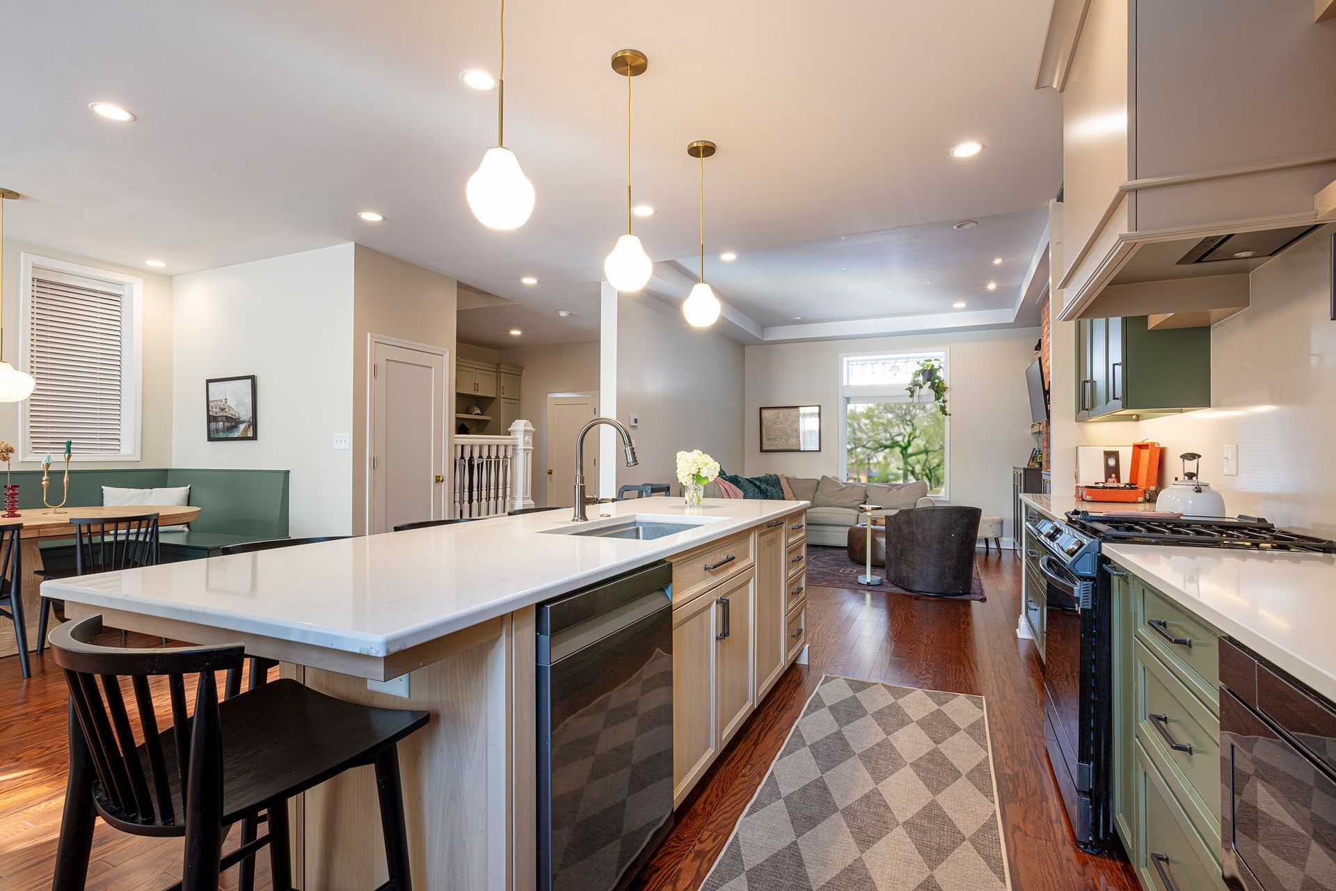 Modern kitchen with large island, pendant lights, and patterned rug in a bright open-plan interior