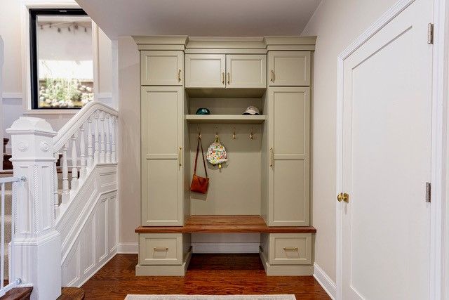 Built-in hallway mudroom bench with storage cabinets in a bright white entryway.