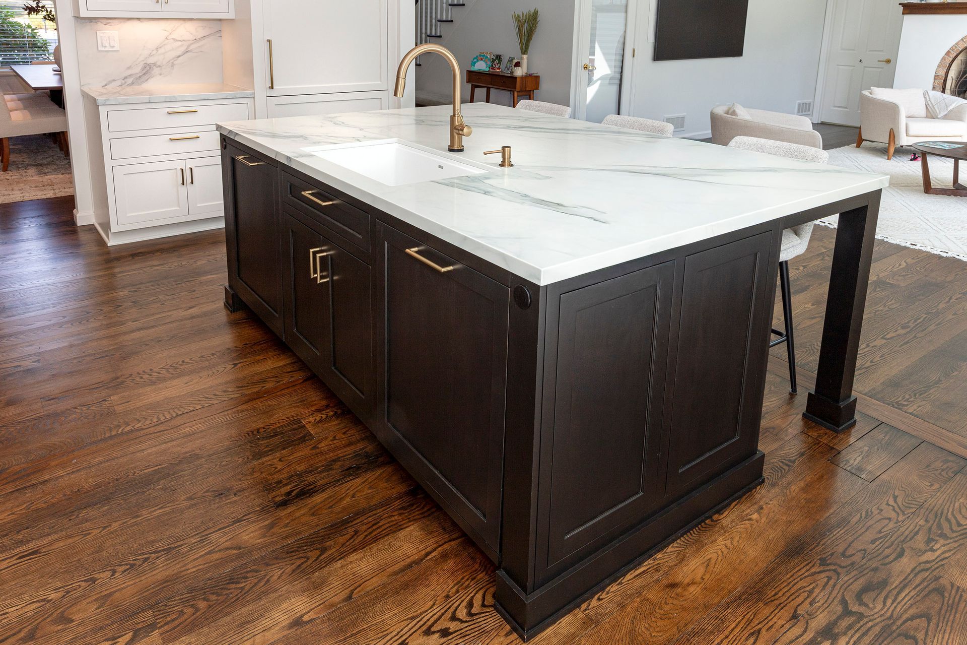 Large dark kitchen island with white countertop and sink in a bright modern kitchen