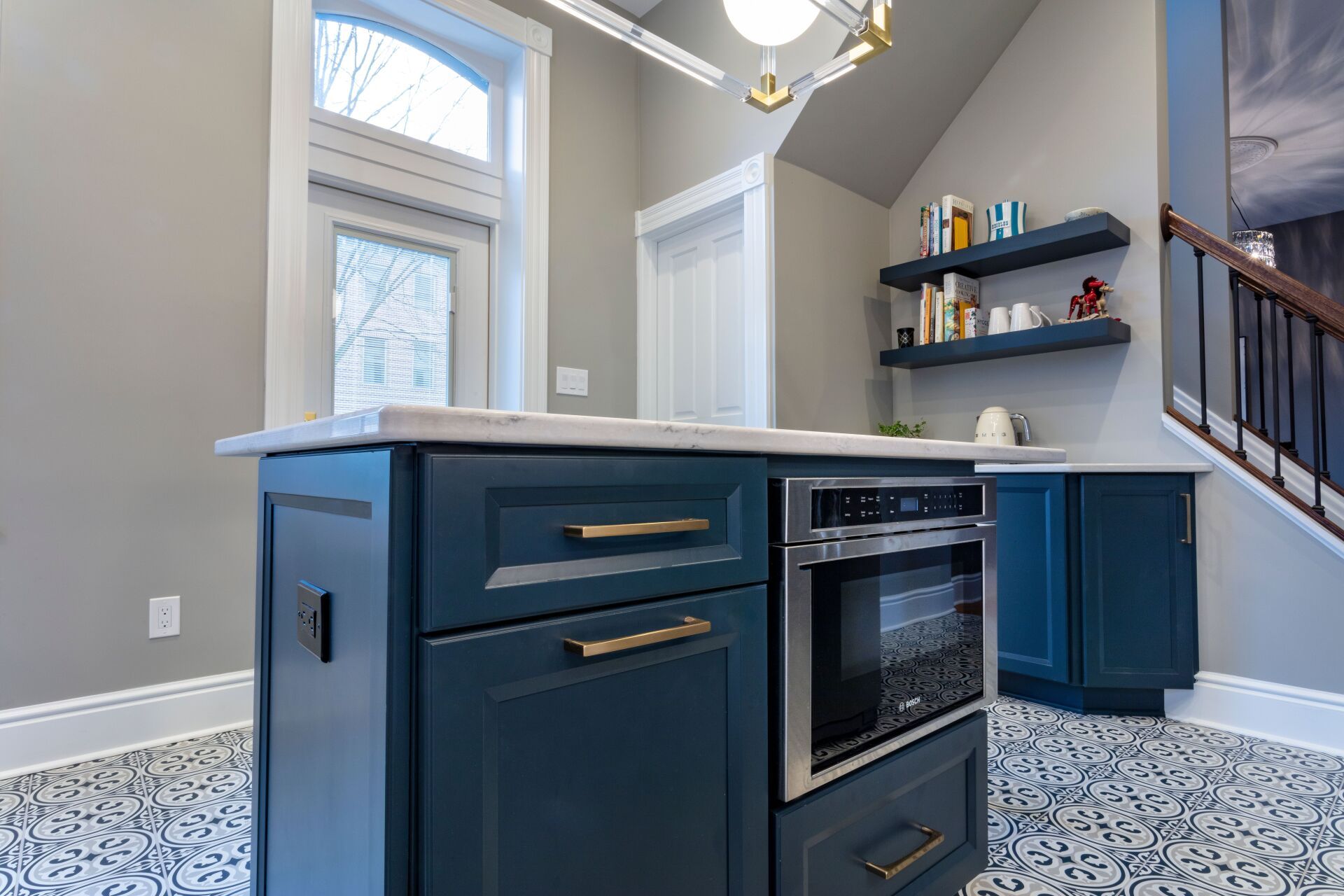 Modern kitchen island with dark blue cabinets, white countertop, and patterned tile floor in a bright home interior