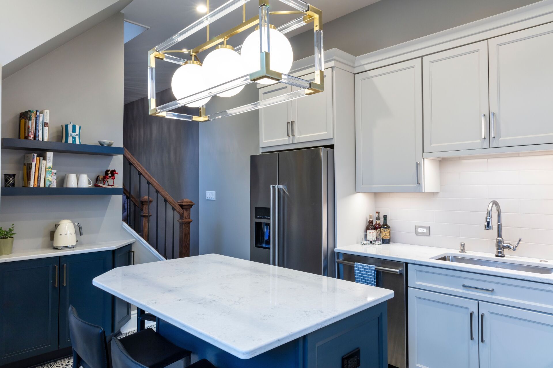 Modern kitchen with white cabinets, blue island, stainless fridge, and pendant lights