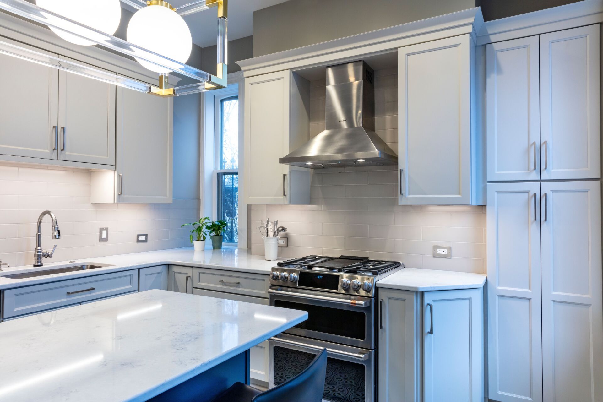 Bright modern kitchen with white cabinets, stainless steel appliances, and a marble island