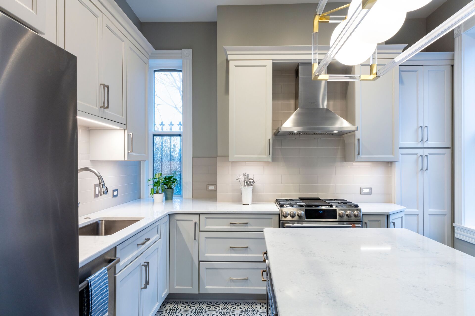 Bright modern kitchen with white cabinets, stainless steel appliances, and a large marble island