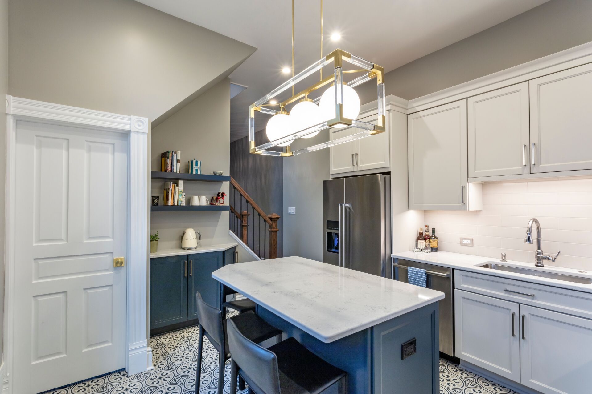 Modern kitchen with white cabinets, blue island, pendant light, and patterned floor