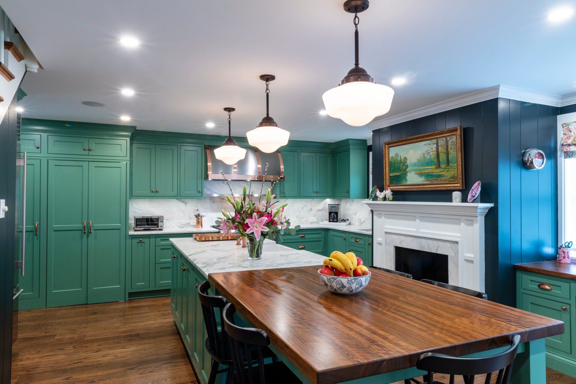 Bright kitchen with teal cabinets, white fireplace, and a wooden island topped with flowers.