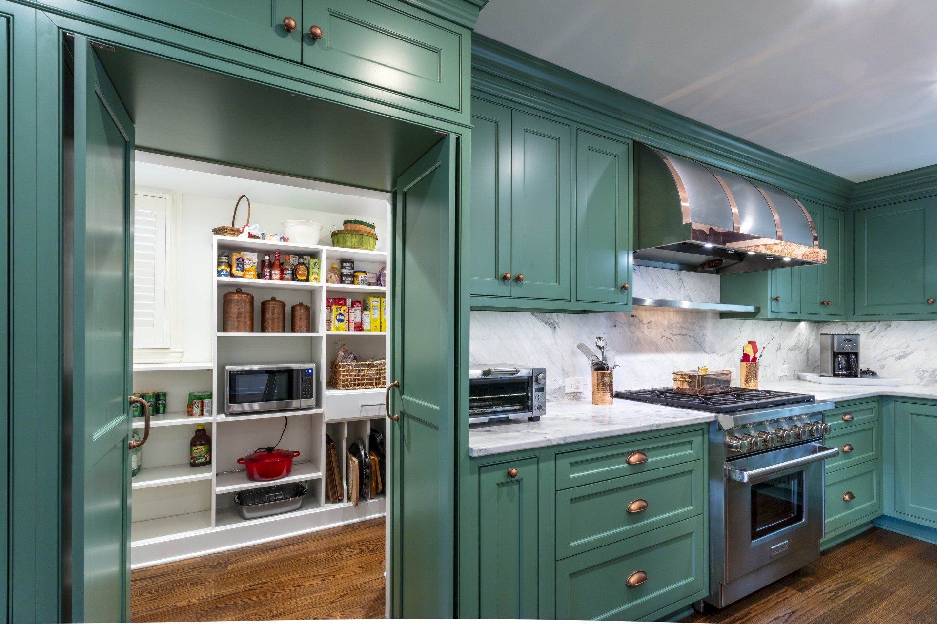 Teal kitchen with open pantry, marble countertops, and stainless steel stove and hood