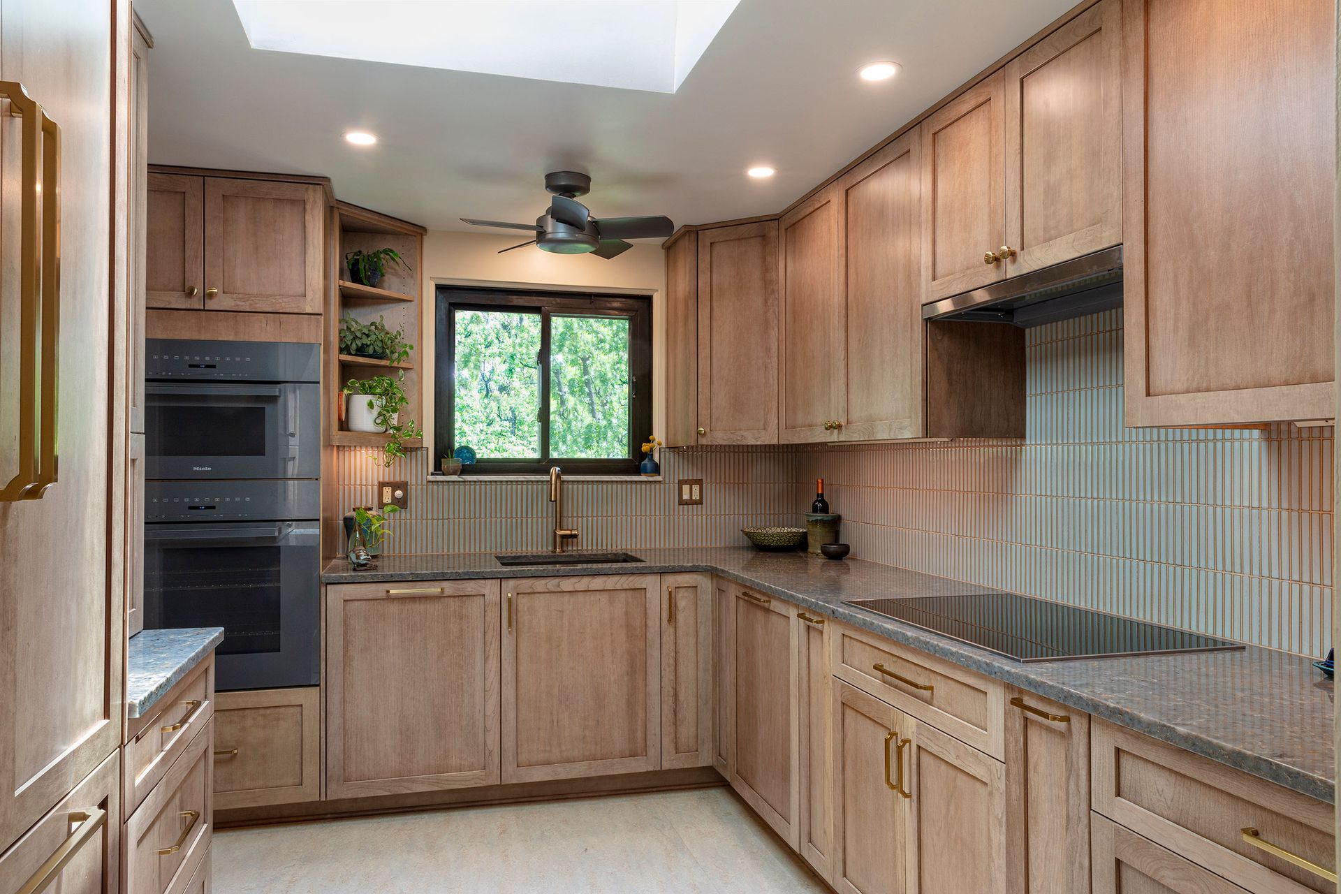 Modern kitchen with wood cabinets, granite countertops, stainless appliances, and a window over the sink.
