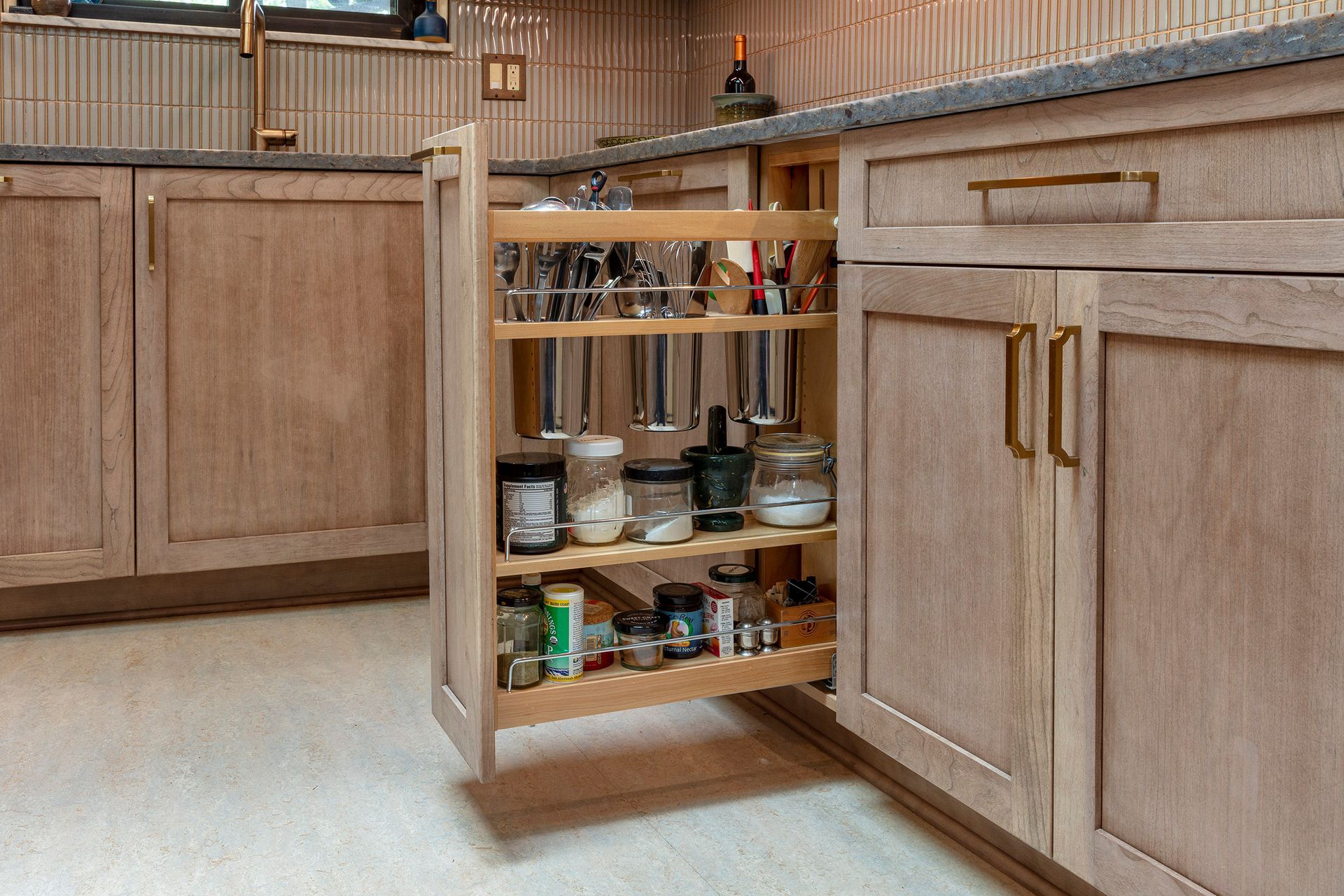 Kitchen cabinet with a pull-out spice rack organizer in a light wood kitchen