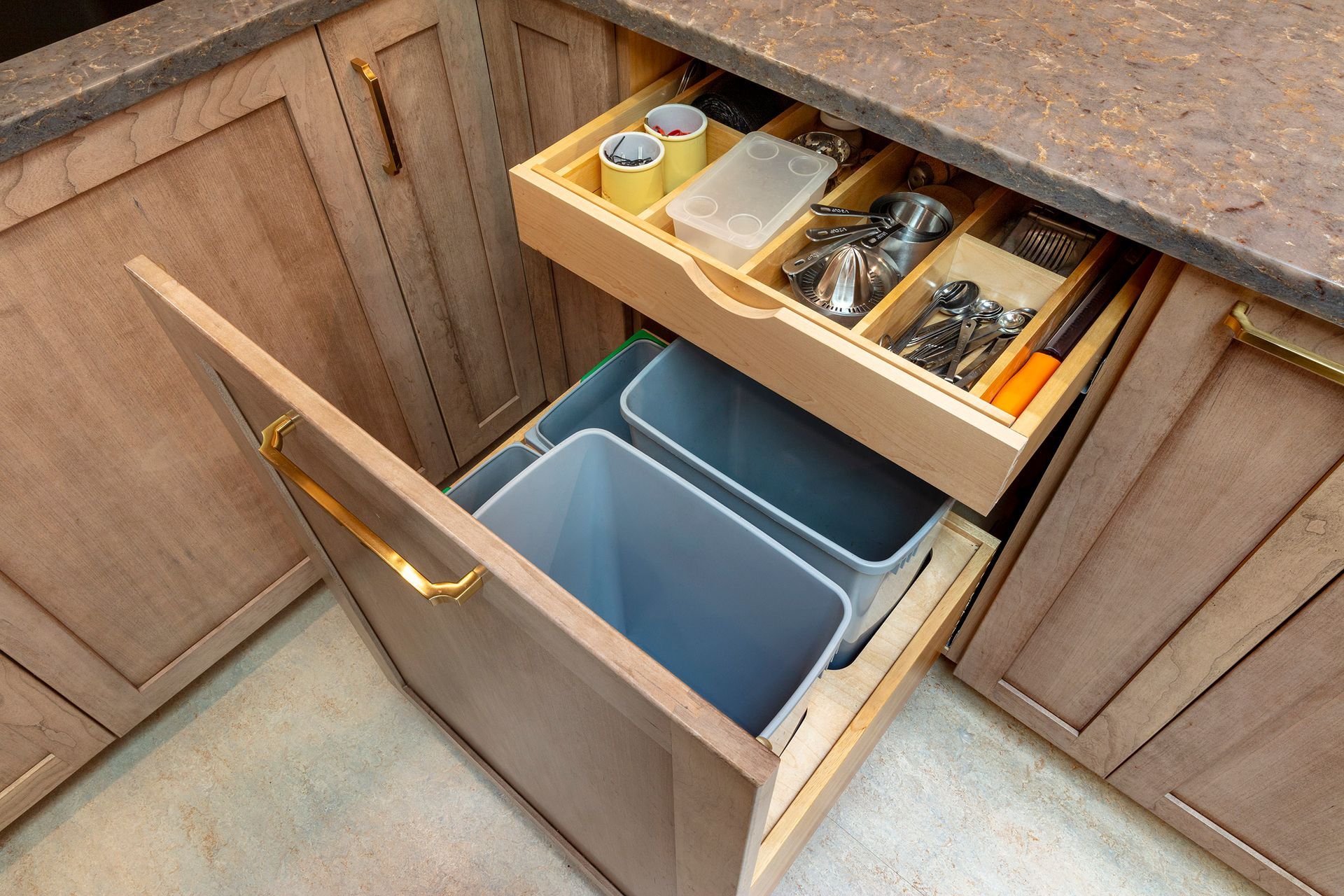 Open kitchen cabinet with pull-out trash bins and organized sink drawers above.