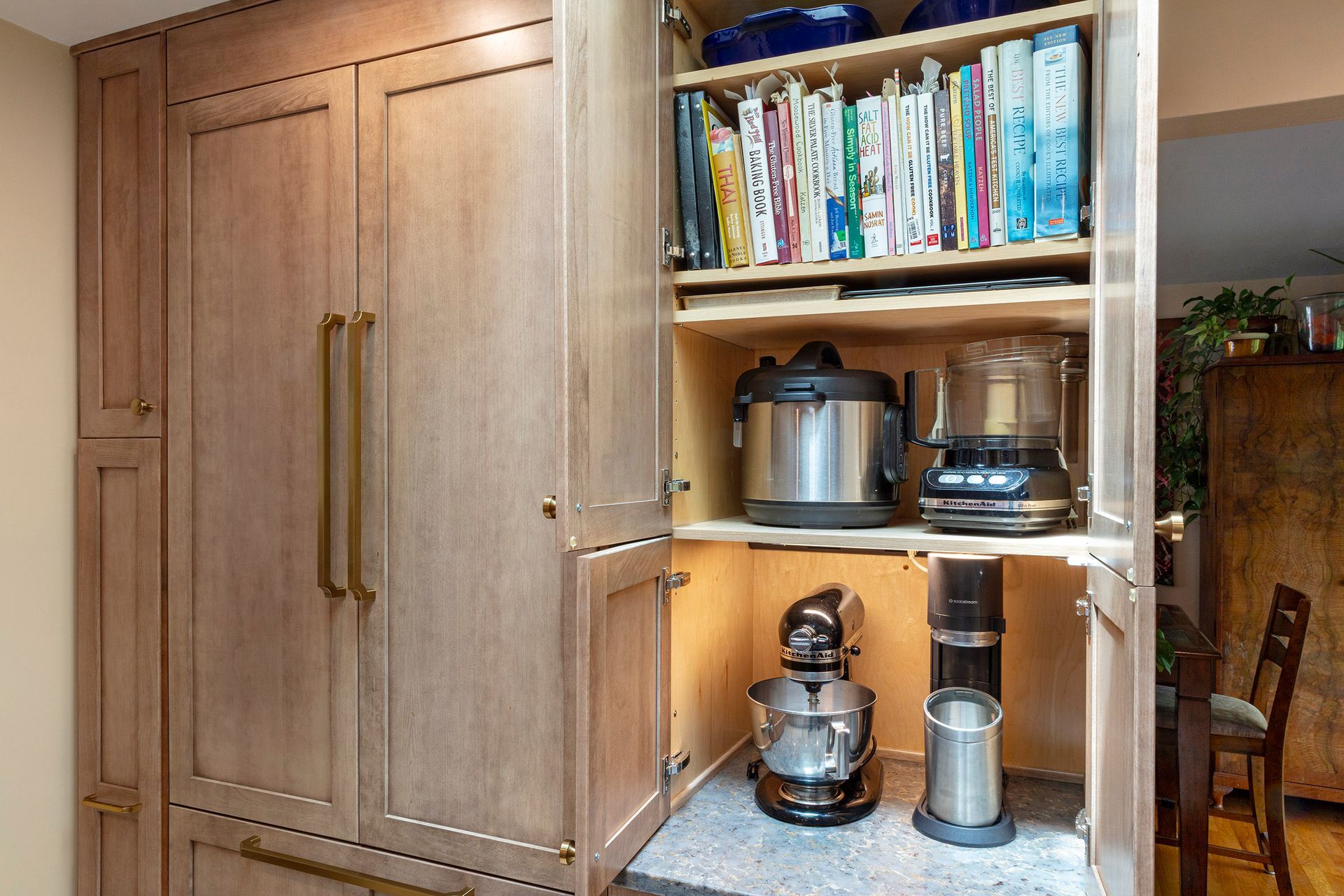 Built-in kitchen cabinet with books, small appliances, and a mixer on lit shelves