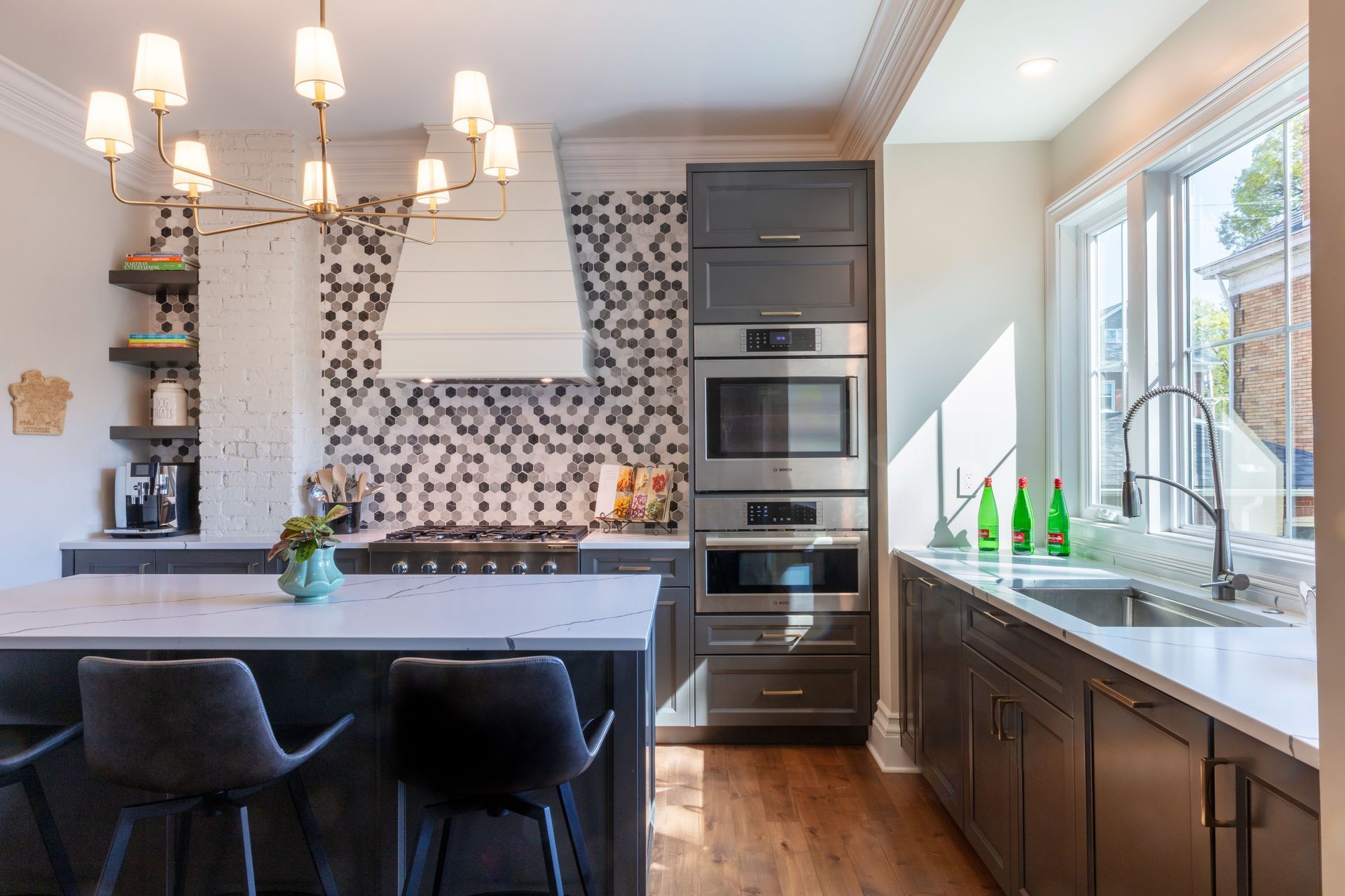 Modern kitchen with dark cabinets, mosaic backsplash, island seating, and large window over the sink