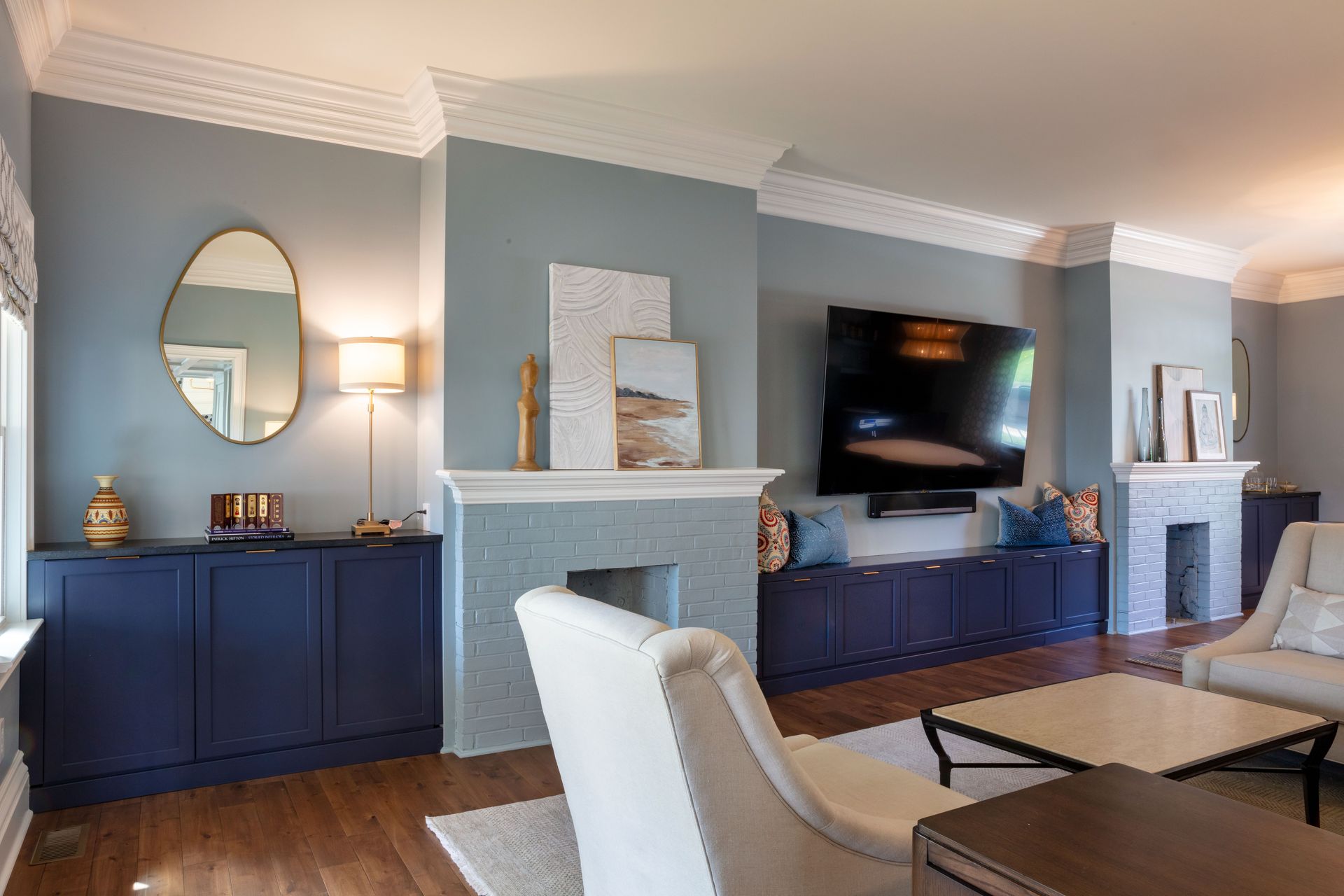 Living room with blue walls, fireplace, TV, sideboards, and a light chair in the foreground