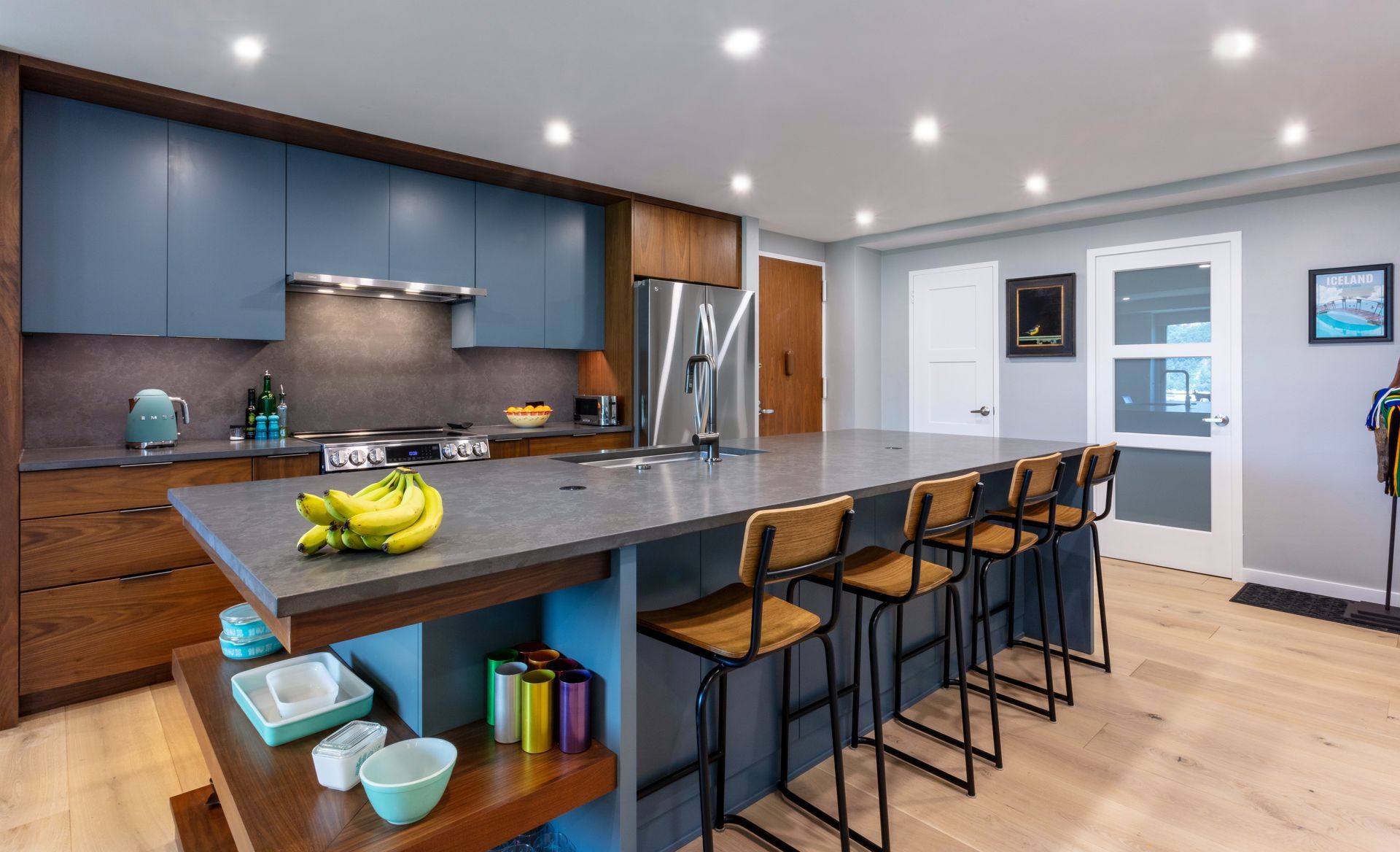 Modern kitchen with a large island, barstools, stainless-steel appliances, and blue cabinets