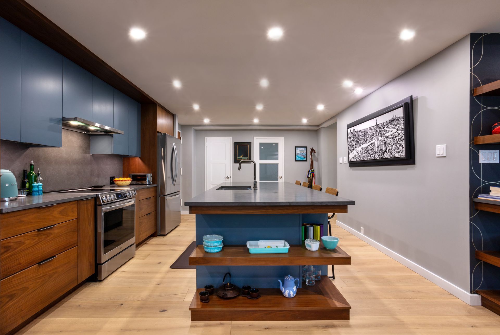 Modern kitchen with dark wood cabinets, island, recessed lights, and open shelving in a bright open-plan space