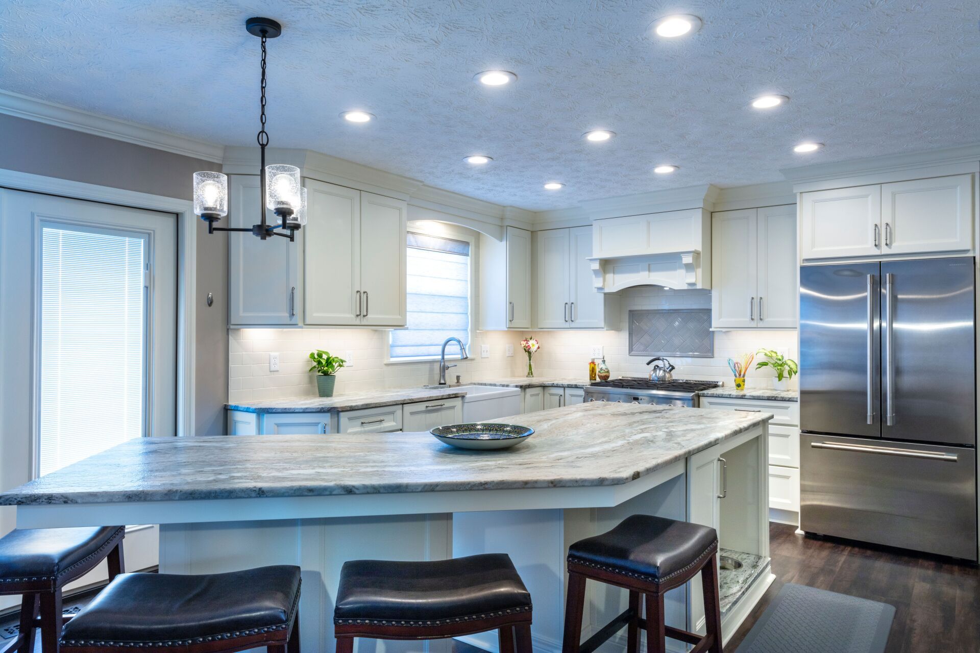 Bright modern kitchen with white cabinets, marble island, and stainless steel appliances