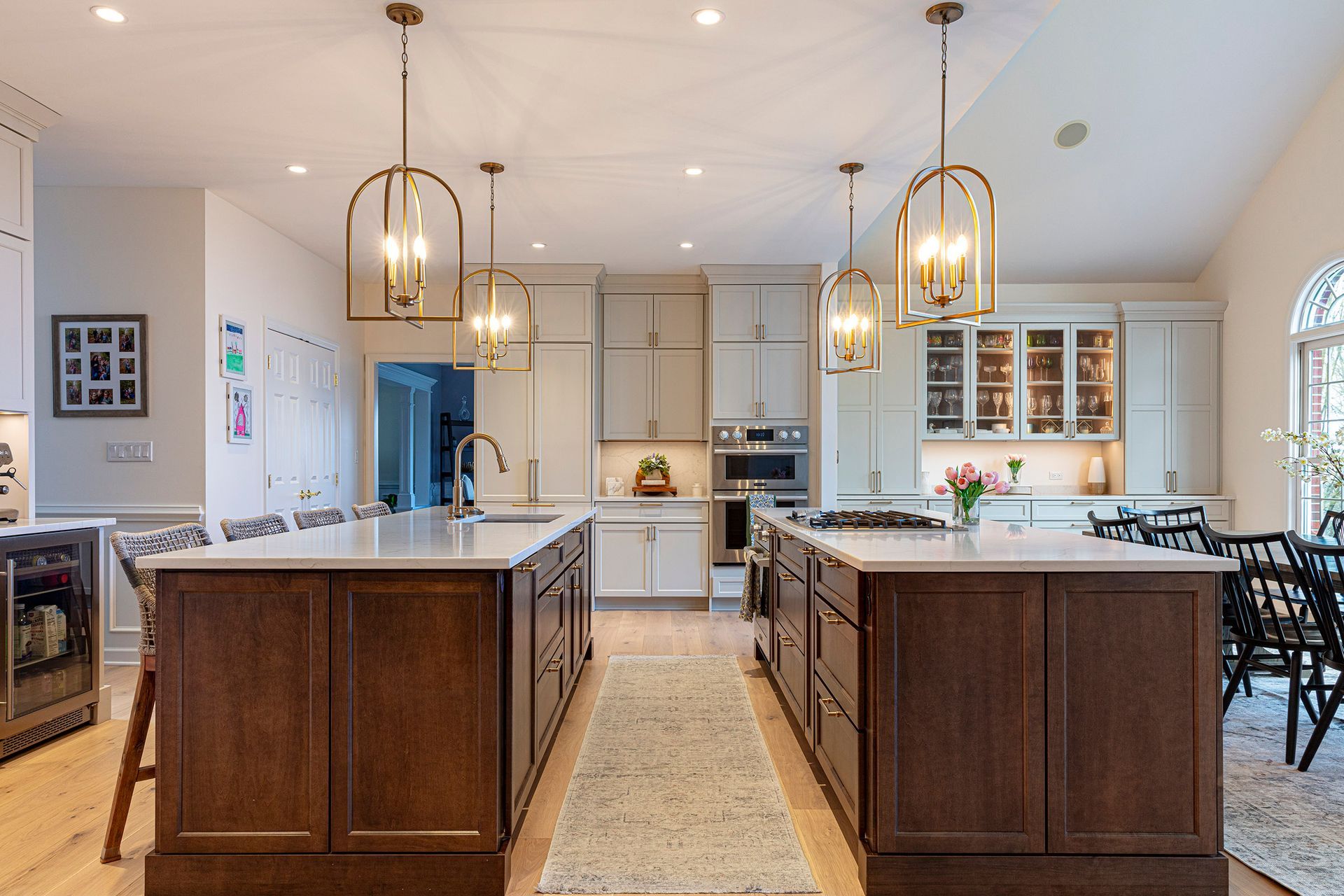 Bright modern kitchen with two dark wood islands, pendant lights, and white cabinetry
