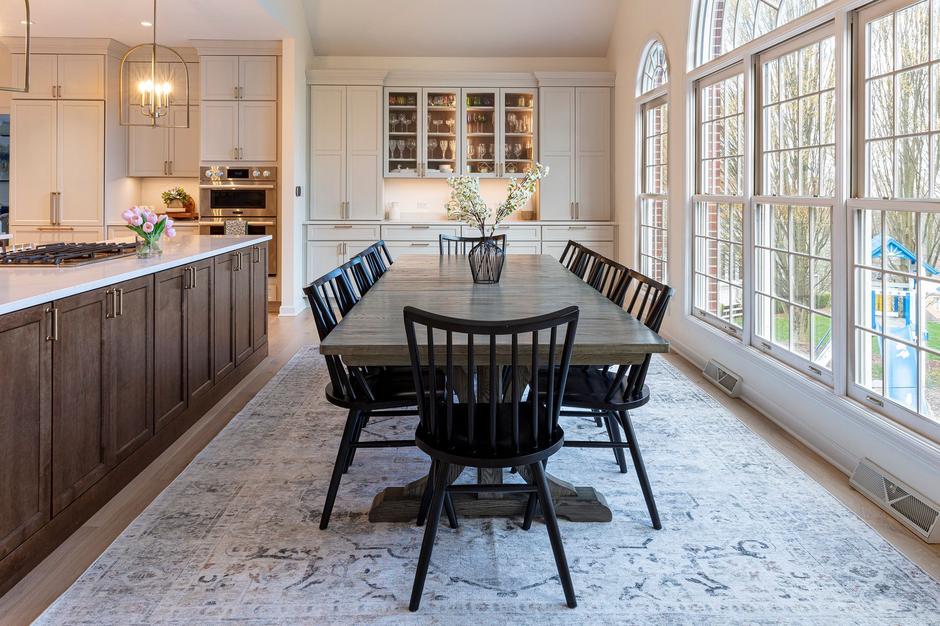 Bright dining room with a dark wood table, black chairs, and large windows letting in natural light