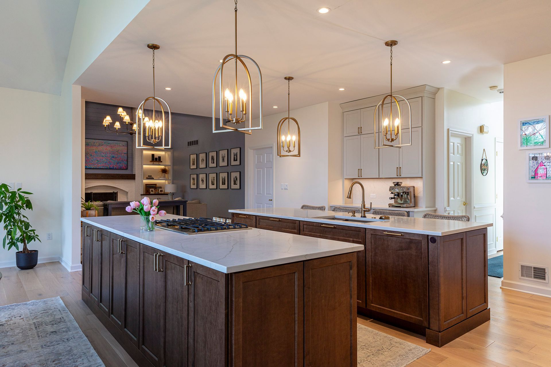 Modern kitchen with dark wood island, pendant lights, and marble countertops in a bright open-plan home