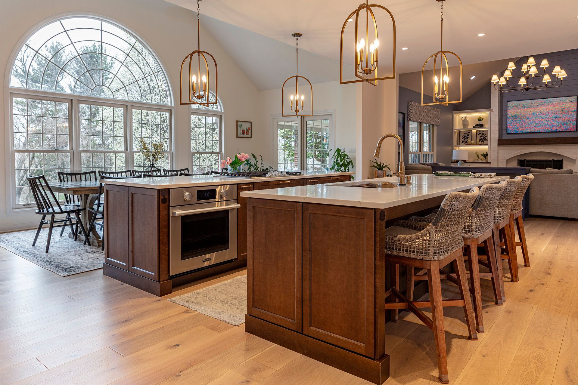 Modern kitchen with wood island, bar stools, pendant lights, and large arched windows
