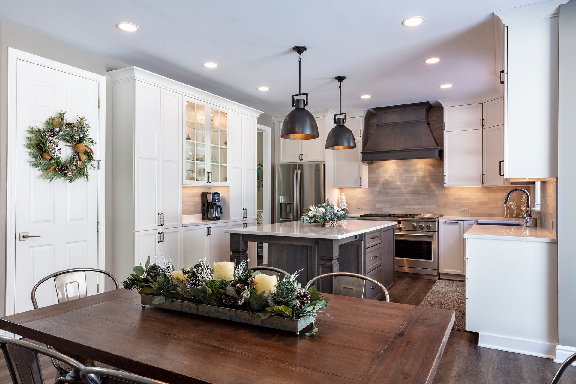 Bright modern kitchen with white cabinets, dark island, and dining table with floral centerpiece