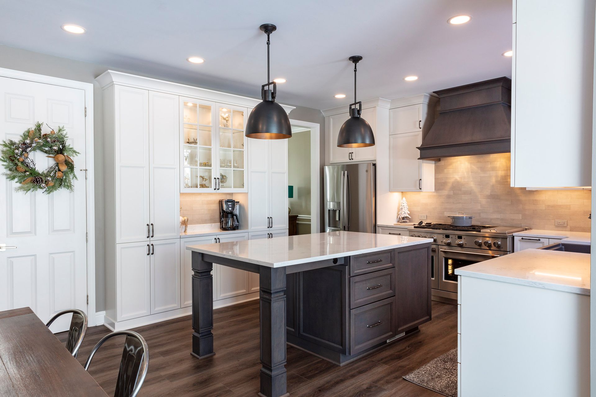 Bright modern kitchen with white cabinets, dark island, pendant lights, and stainless steel appliances