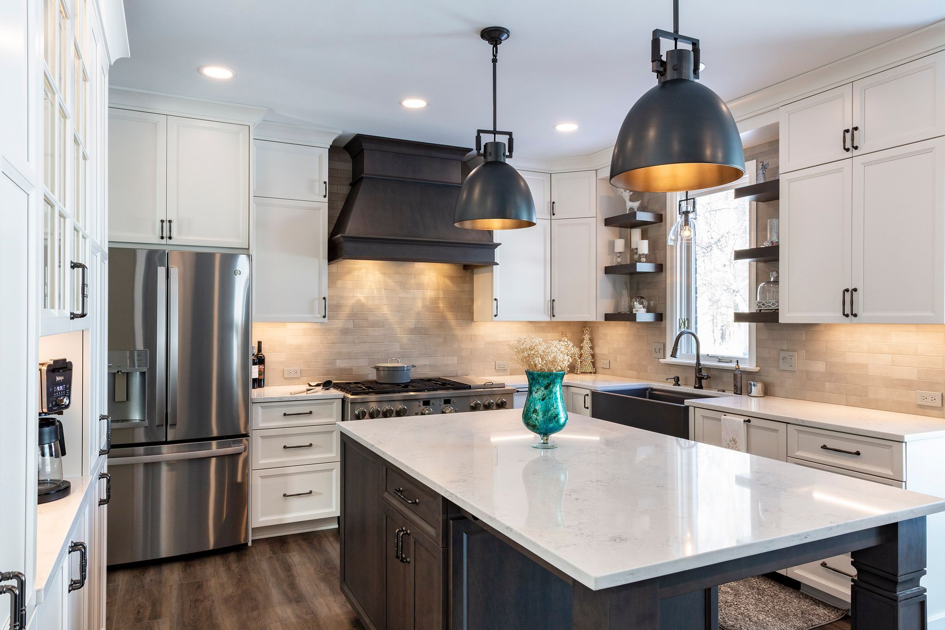 Modern kitchen with white cabinets, stainless steel appliances, large island, and black pendant lights.