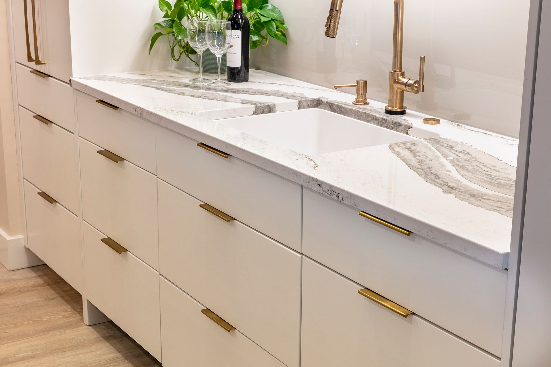 Modern white bathroom vanity with double sinks, brass faucets, and a marble countertop