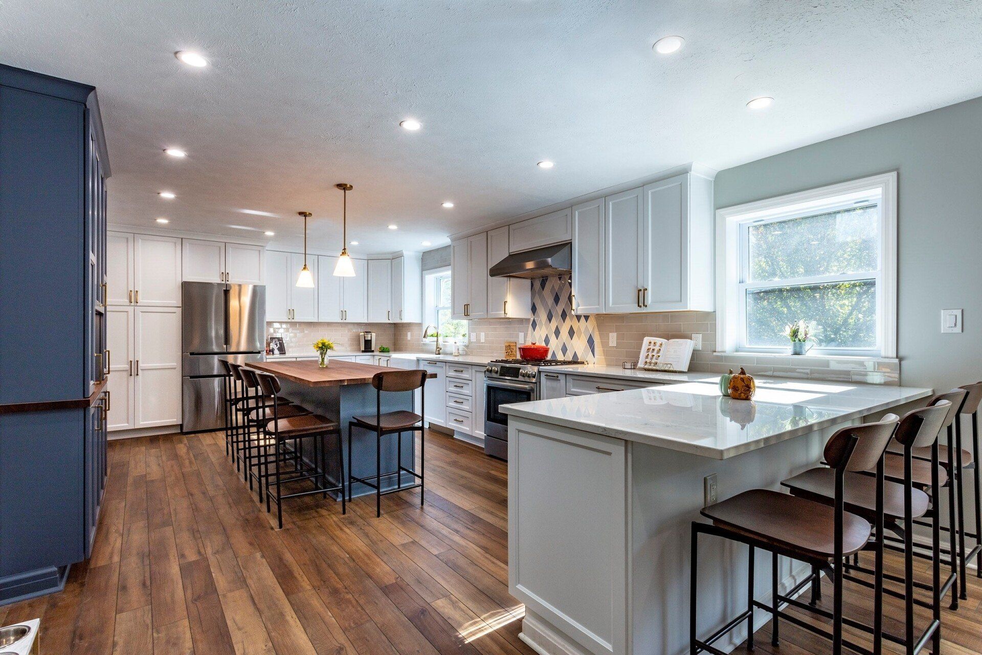 Bright modern kitchen with white cabinets, island seating, and stainless steel appliances