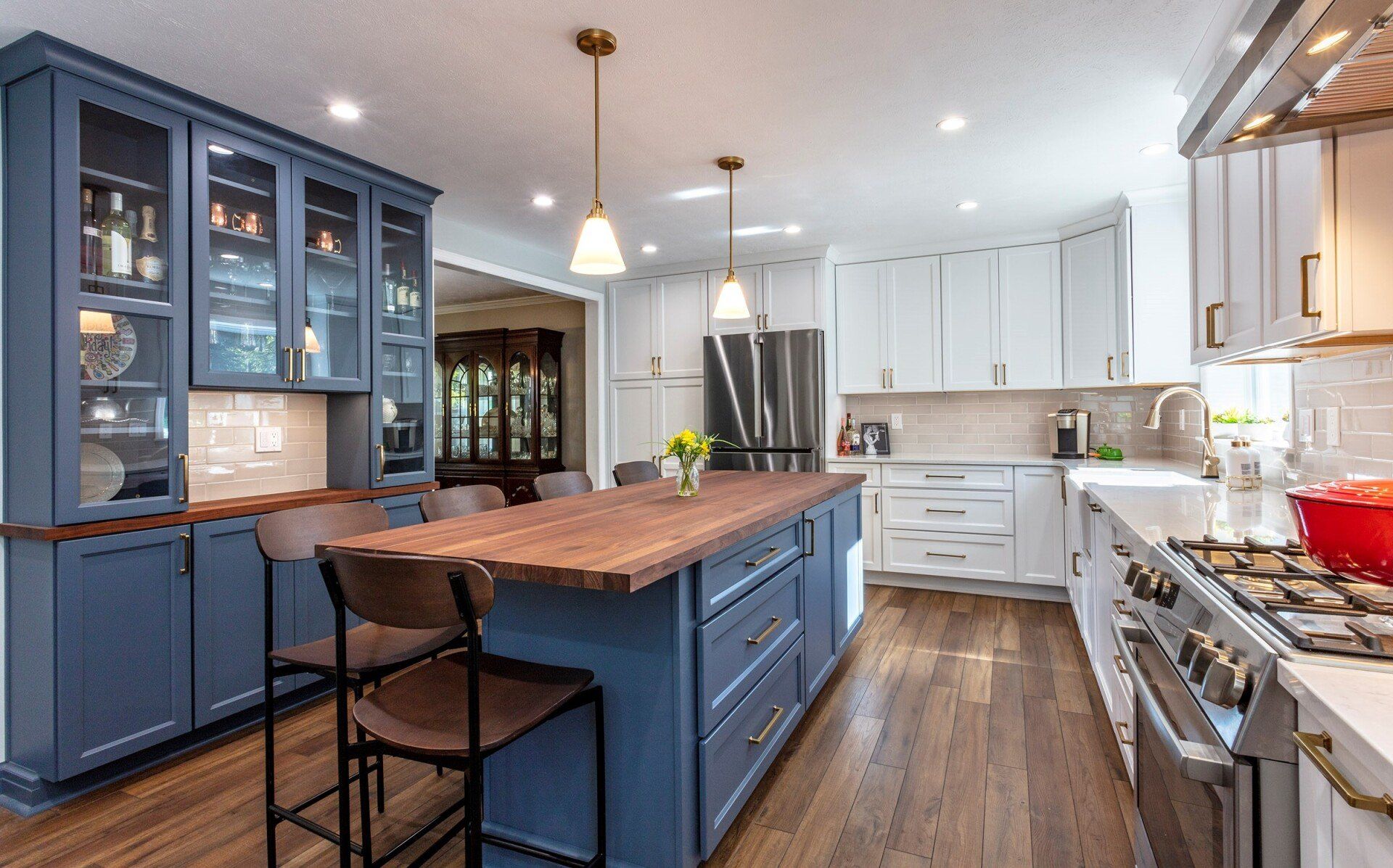 Bright modern kitchen with blue cabinets, a central island, wood floors, and stainless steel appliances